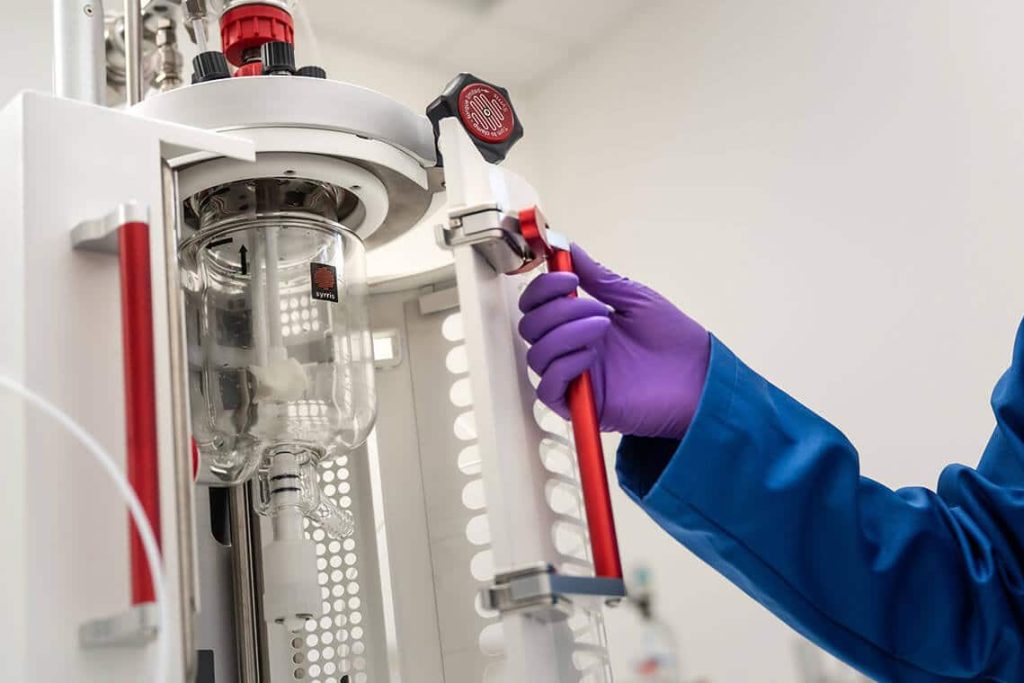 A chemist opening up the safety enclosure of Syrris Atlas HD 3 Bar Pressure System