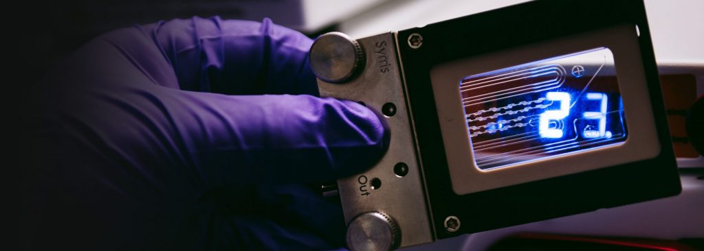 A chemist holding a Syrris Asia Flow chemistry glass chip