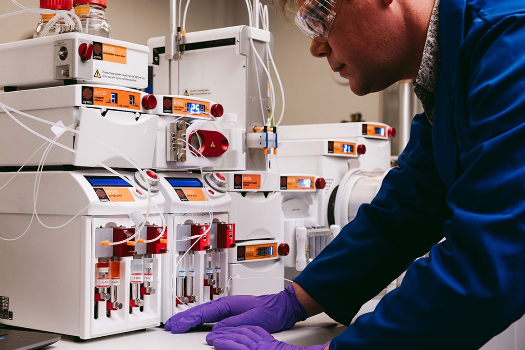 Syrris Asia chemist in lab with syringe pump