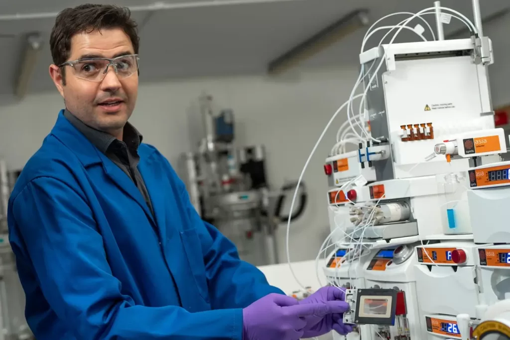 Syrris chemist in lab using micro reactor for flow chemistry in drug discovery