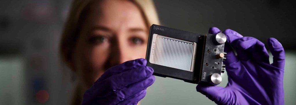 A chemist holding a Syrris Asia Flow chemistry glass chip